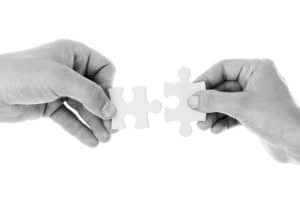 Hands bringing puzzle pieces together