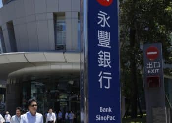 Pedestrians exit the SinoPac Financial Holdings Co. building in Taipei, Taiwan, on Wednesday, July 17, 2013. Taiwan should remove restrictions on mainland Chinas companies and its currency so the island can become an offshore hub for the yuan, SinoPac Financial Holdings Co. said. Photographer: Ashley Pon/Bloomberg