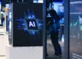 An Artificial Intelligence (AI) logo at the Siemens AG booth at the Hannover Messe 2026 trade fair in Hannover, Germany, on Sunday, April 19, 2026. Siemens will prioritize artificial-intelligence investments in the US and China if the European Union doesnt adapt its restrictive regulations, according to Chief Executive Officer Roland Busch.