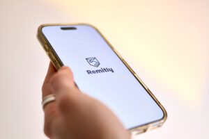 A hand holding a mobile phone with the Remitly online remittance service app displayed on it