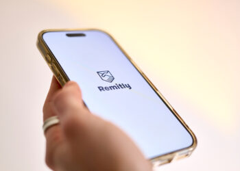 A hand holding a mobile phone with the Remitly online remittance service app displayed on it
