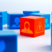 Multiple blue cubes showing the silhouettes of people, with one red cube showing a silhouette wearing a mask and with an alert symbol