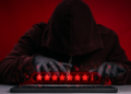 a shadowy figure types a password into a keyboard
